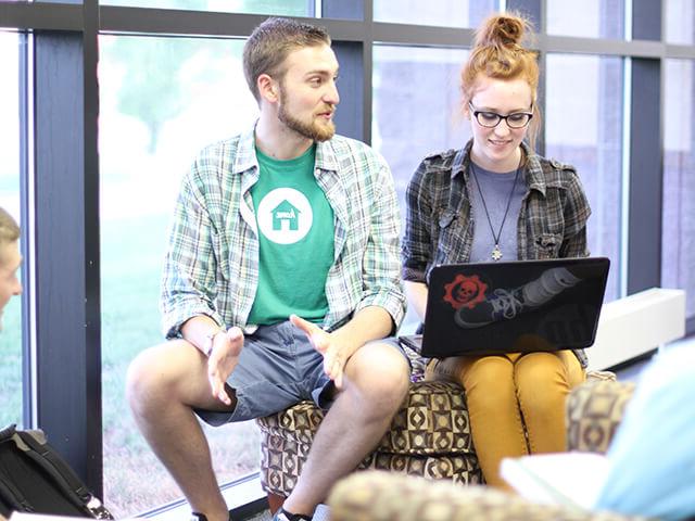 两个学生在图书馆用笔记本电脑一起工作